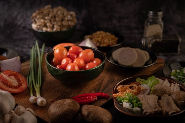 I pomodori nella tazza nera con cipolline, peperoni, pomodori e cipolle rosse.