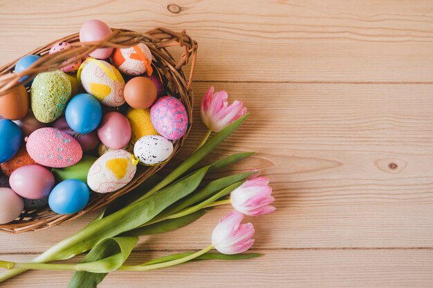 I tulipani si avvicinano al cestino con le uova di Pasqua