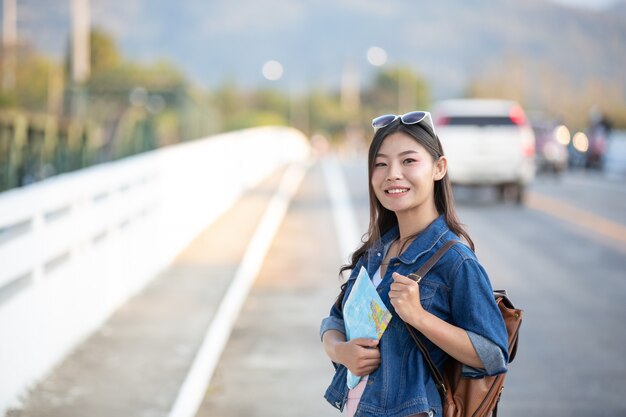 I turisti femminili a disposizione hanno una mappa di viaggio felice.