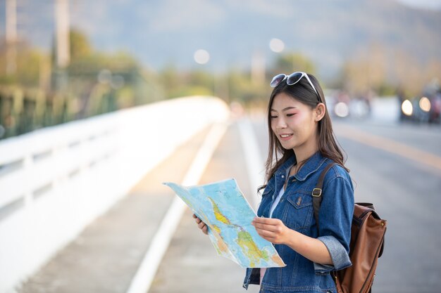 I turisti femminili a disposizione hanno una mappa di viaggio felice.