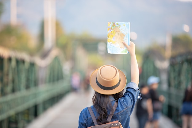 I turisti femminili a disposizione hanno una mappa di viaggio felice.