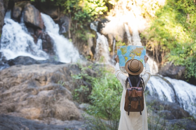 I turisti femminili a disposizione hanno una mappa di viaggio felice.