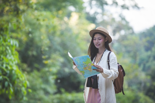 I turisti femminili a disposizione hanno una mappa di viaggio felice.