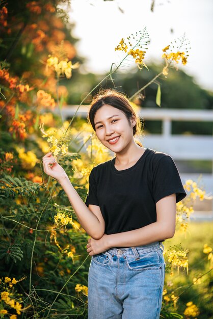 I turisti femminili stanno e prendono i fiori nel giardino.