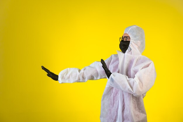 Igienizzante in speciale divisa preventiva ferma pericolo proveniente da sinistra su giallo.