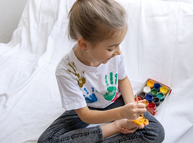 Il bambino disegna un motivo sul suo piede con un pennello.