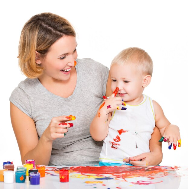 Il bambino felice disegna sul volto di sua madre isolato su bianco.