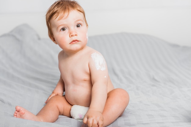 Il bambino seduto si spalma con la lozione