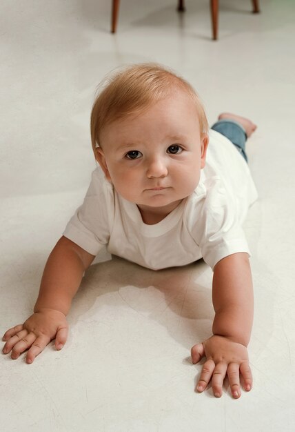 Il bambino sveglio con i grandi occhi in jeans e camicia bianca sembra interessato