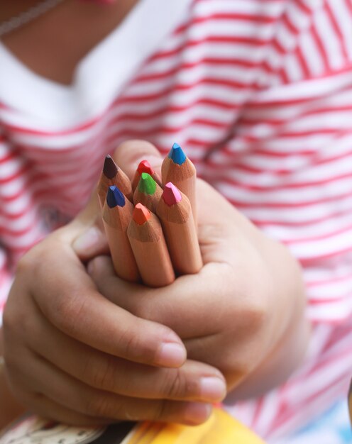 Il bambino tiene matite di colore su piccola mano