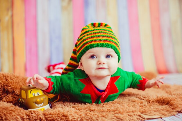 Il bambino vestito come un elfo si trova sul tappeto morbido