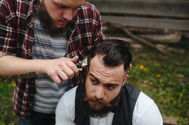 Il barbiere rade un uomo barbuto in un'atmosfera vintage
