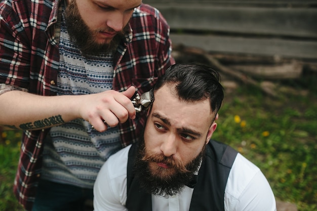 Il barbiere rade un uomo barbuto in un'atmosfera vintage
