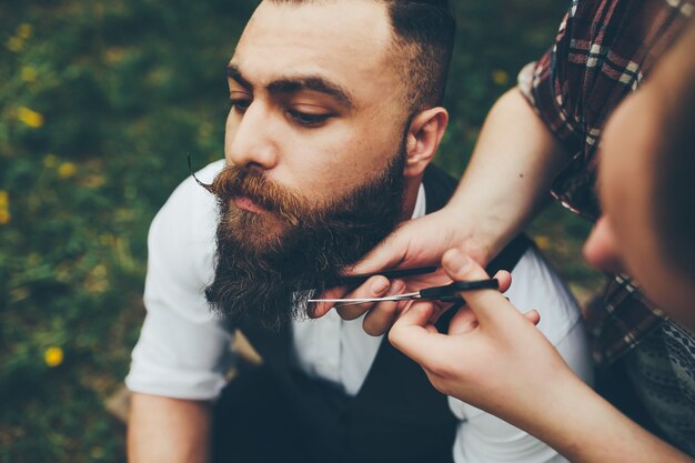 Il barbiere rade un uomo barbuto in un'atmosfera vintage