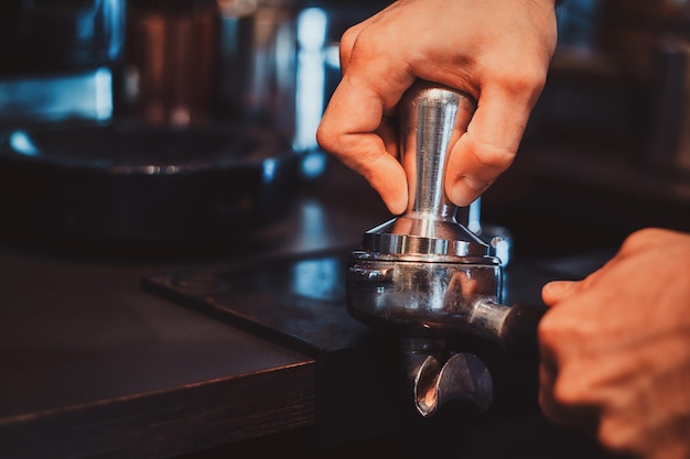 Il barista di talento sta preparando il caffè per i clienti in un ristorante elegante usando la macchina del caffè.