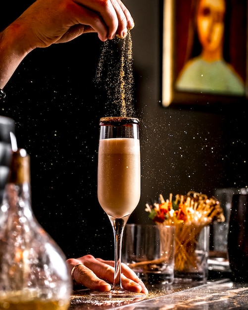 Il barista spruzza glitter dorati nel cocktail in un bicchiere di champagne