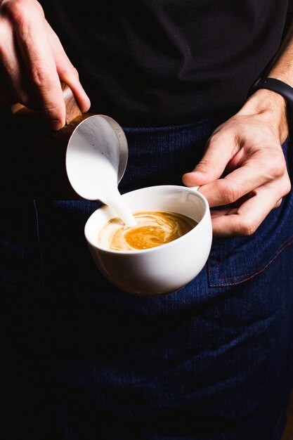 Il barista sta preparando il cappuccino con schiuma di latte