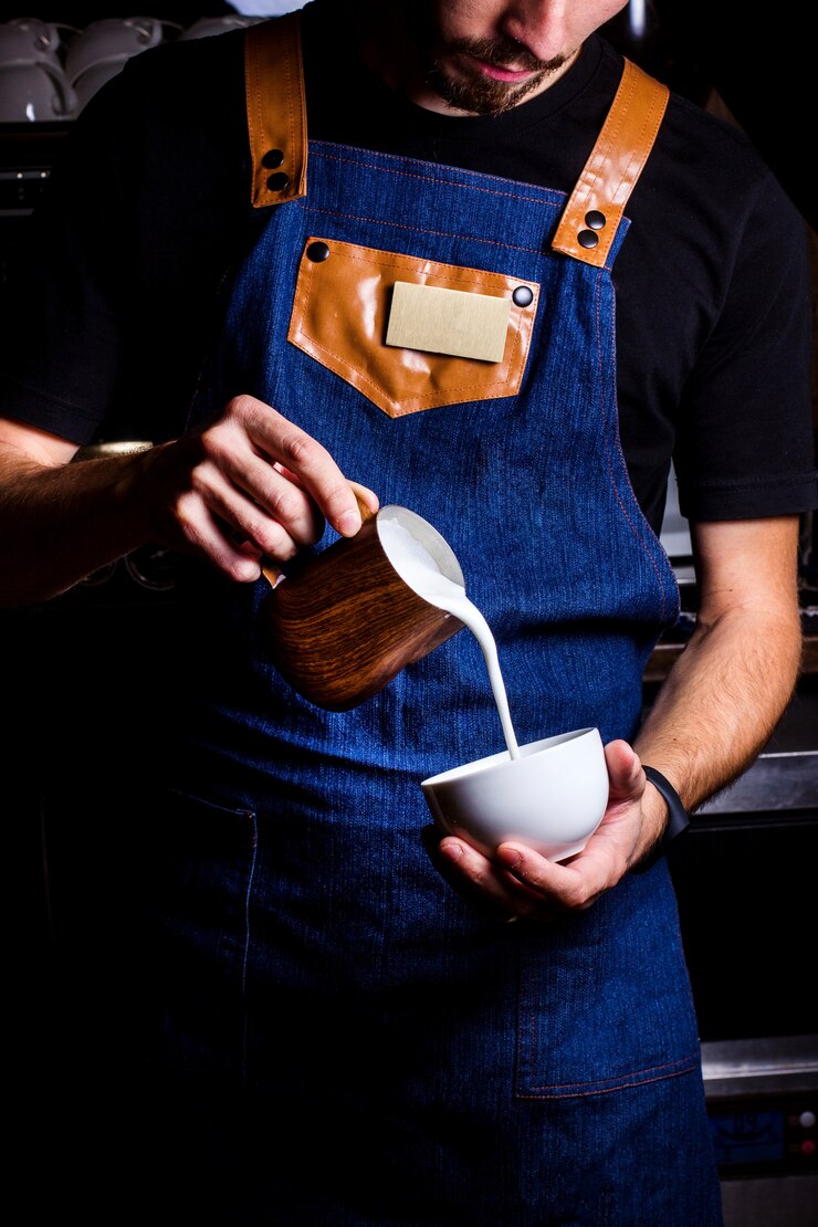 Foto gratuito il barista versa il latte nel caffè.