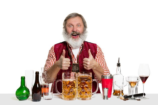 Il barman maschio esperto senior con birra a isolato sulla parete bianca. Giornata internazionale del barman, bar, alcol, ristorante, birra, festa, pub, concetto di celebrazione del giorno di San Patrizio