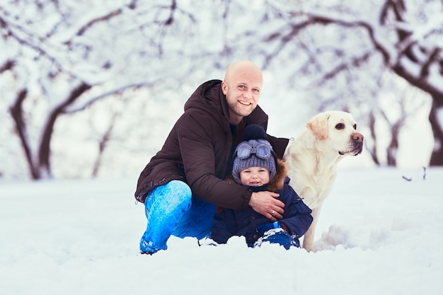 Il bellissimo padre, figlio e cane seduto sulla neve