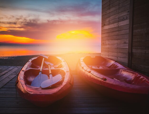 Il bellissimo tramonto con coppia rosso barca Kayak con il sole giaceva.