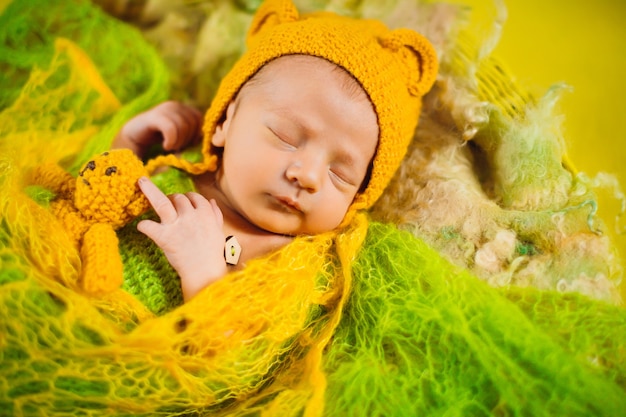 Il bello bambino dorme sotto la sciarpa verde nel canestro