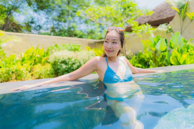 Il bello giovane sorriso asiatico della donna del ritratto felice si distende e svago nella piscina