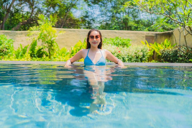 Il bello giovane sorriso asiatico della donna del ritratto felice si distende e svago nella piscina