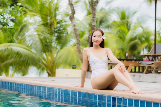Il bello giovane sorriso asiatico della donna del ritratto si rilassa intorno alla piscina all'aperto nell'hotel della località di soggiorno in viaggio di viaggio di vacanza di festa