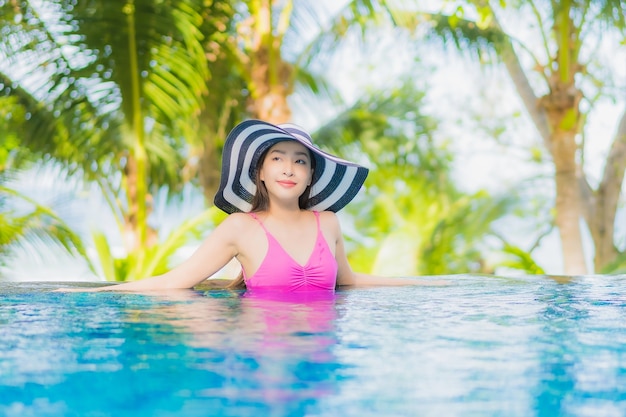 Il bello giovane sorriso asiatico della donna del ritratto si rilassa intorno alla piscina all'aperto nell'hotel della località di soggiorno in viaggio di viaggio di vacanza di festa