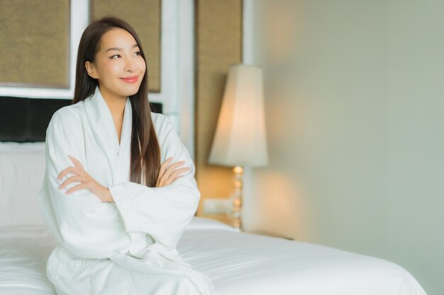 Il bello giovane sorriso asiatico della donna del ritratto si rilassa sul letto nell'interno della camera da letto
