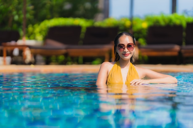 Il bello giovane svago asiatico della donna del ritratto si rilassa sorriso e felice intorno alla piscina nella località di soggiorno dell&#39;hotel