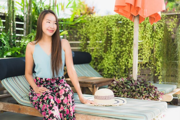 Il bello sorriso felice della giovane donna asiatica e si rilassa nella piscina