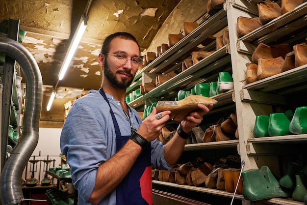 Il calzolaio barbuto con gli occhiali ha trovato la forma di scarpa giusta per la sua nuova collezione.