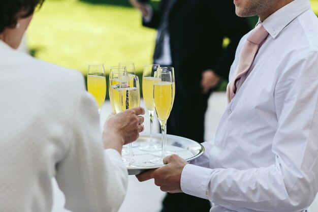 Il cameriere vestito di bianco porta gli occhiali con lo champagne