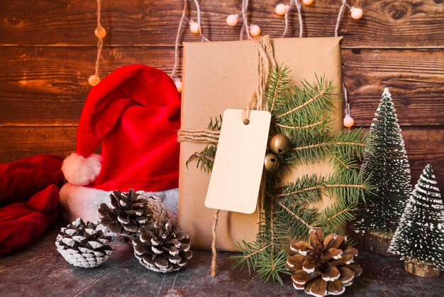 Il cappello di Natale vicino al contenitore di regalo ha decorato il ramoscello dell&#39;abete con l&#39;etichetta