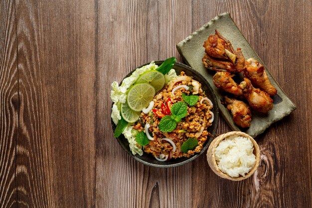 Il cibo tailandese con carne di maiale macinata piccante serve con riso appiccicoso e pollo fritto