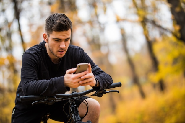 Il ciclista felice dell'uomo guida nella foresta soleggiata su un mountain bike. Viaggio avventuroso.