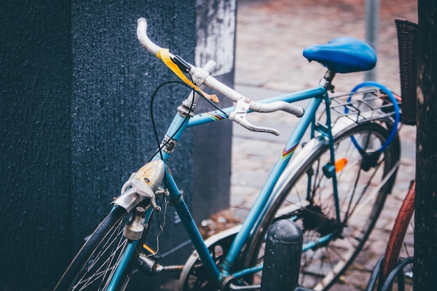 Il colpo selettivo del primo piano di una bicicletta blu ha parcheggiato vicino ad una parete