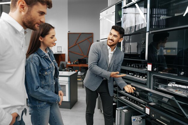 Il commesso maschio aiuta la giovane coppia a scegliere il nuovo elettrodomestico