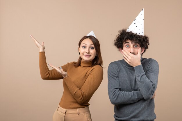 Il concetto del nuovo anno con le giovani coppie felici emozionanti adorabili porta la ragazza del cappello del nuovo anno che osserva sopra