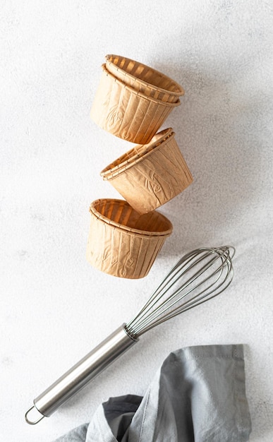 Il concetto di cottura fatta in casa è una frusta per montare e stampi per cupcake su sfondo bianco Zero sprechi Spazio di copia Vista dall'alto Concetto di cottura