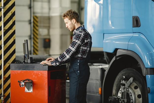 Il conducente controlla la merce. Uomo in uniforme. Camion in garage