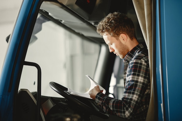 Il conducente di un camion blu e una maglietta in una cella ha portato merci