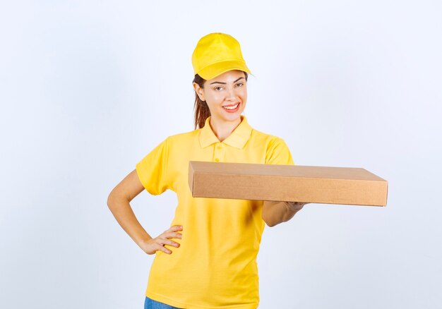 Il corriere femminile in uniforme gialla ha consegnato un pacco di cartone all'indirizzo giusto.