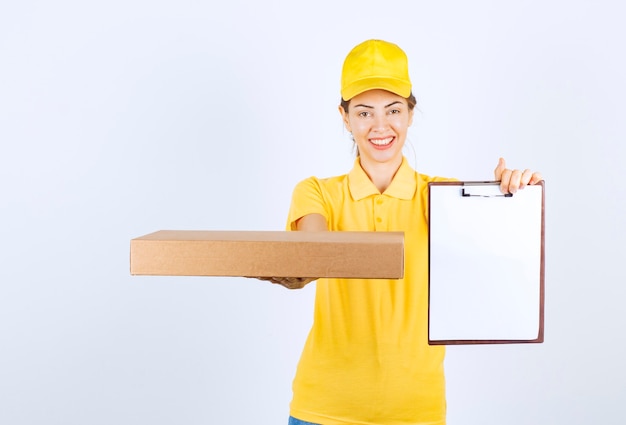 Il corriere femminile in uniforme gialla ha consegnato un pacco e ha chiesto al cliente di firmare.