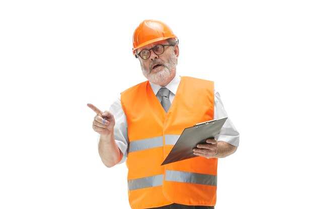Il costruttore in un giubbotto di costruzione e casco arancione in piedi su bianco.