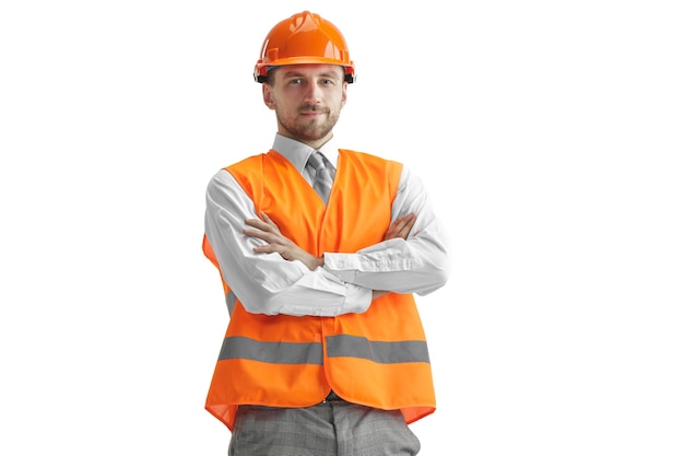 Il costruttore in un giubbotto di costruzione e casco arancione in piedi su sfondo bianco studio. Specialista della sicurezza, ingegnere, industria, architettura, manager, occupazione, uomo d'affari, concetto di lavoro