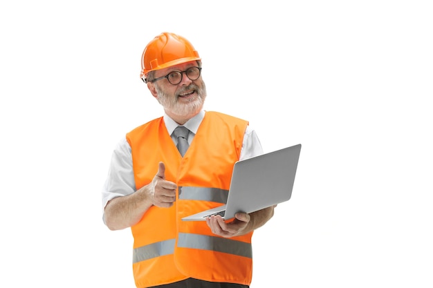 Il costruttore in un giubbotto di costruzione e un casco arancione con laptop