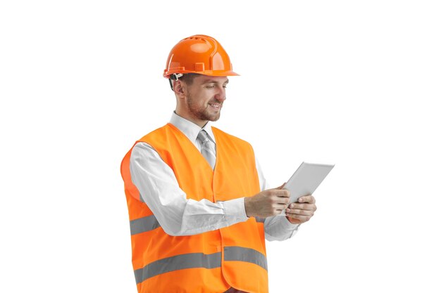 Il costruttore in un giubbotto di costruzione e un casco arancione con tablet. Specialista della sicurezza, ingegnere, industria, architettura, manager, occupazione, uomo d'affari, concetto di lavoro